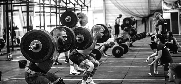 EMT competitors lined up performing weightlifting work with Olympic barbells, black-and-white photograph